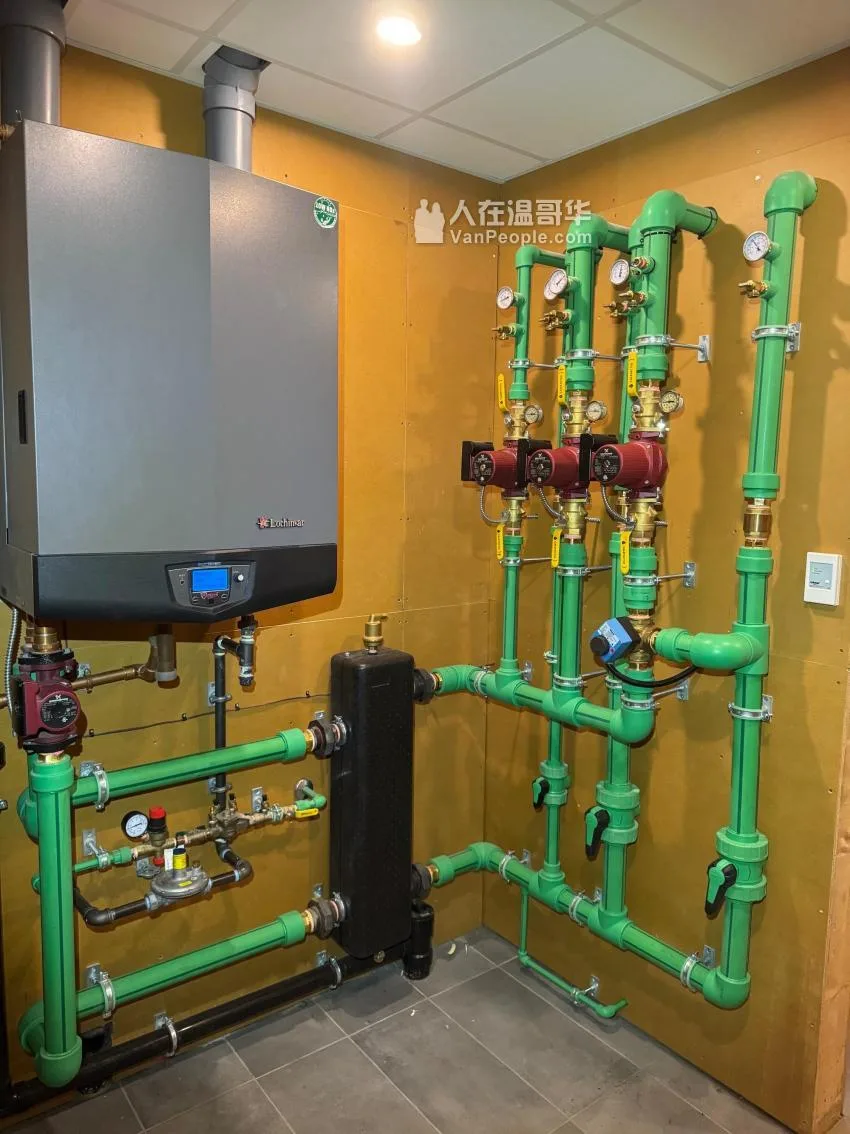 A wall-hung boiler beside a radiant manifold: three circulators, isolation valves and pressure gauges on the loops.